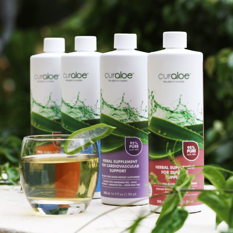Curaloe bottles with a glass of liquid on a natural background