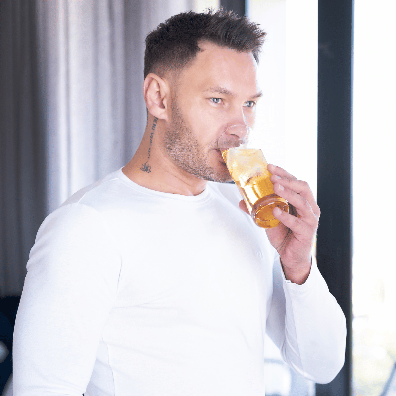 Man drinking aloe vera juice from a glass with a white background