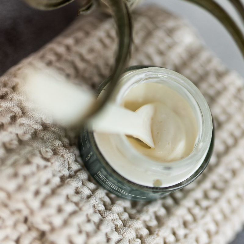 Curaloe Hydra Restore Cream with a spoonful taken out, placed on a textured surface.