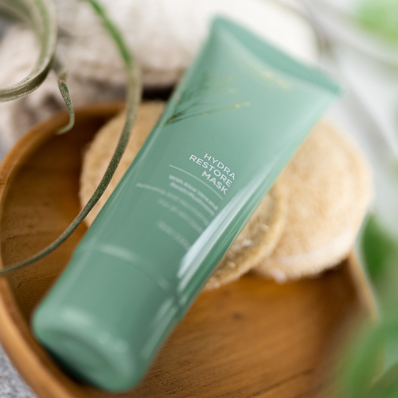 Curaloe Hydra Restore mask on a wooden surface with a blurred natural background