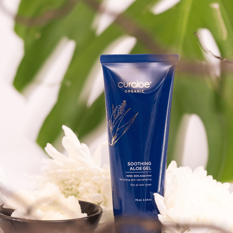 Curaloe Organic soothing aloe gel tube with white flowers and green leaves in the background