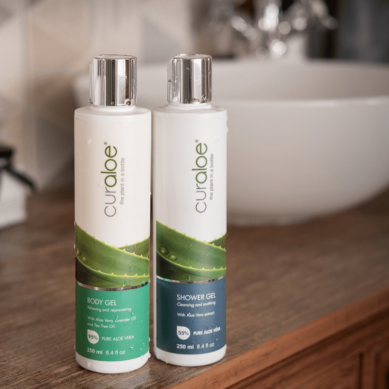 Two bottles of Curaloe body and shower gel on a bathroom counter.