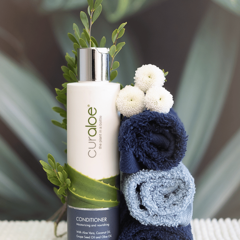 Curlaoe conditioner bottle with towels and flowers on a blurred background