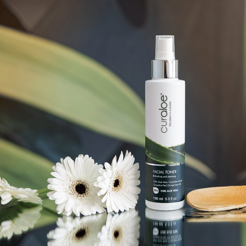 Curology facial toner bottle with white flowers on a reflective surface