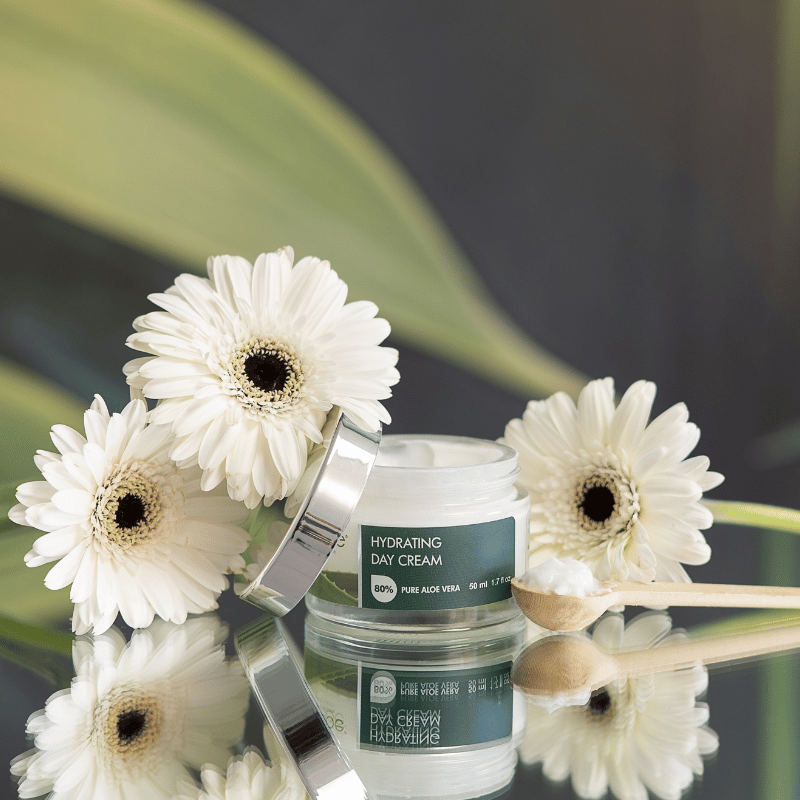 Hydrating day cream jar with white flowers on a reflective surface