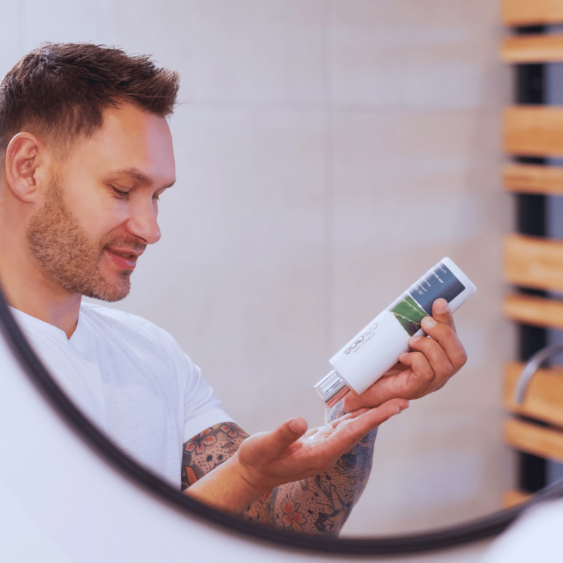 Man using Curaloe Facial Wash in front of a mirror