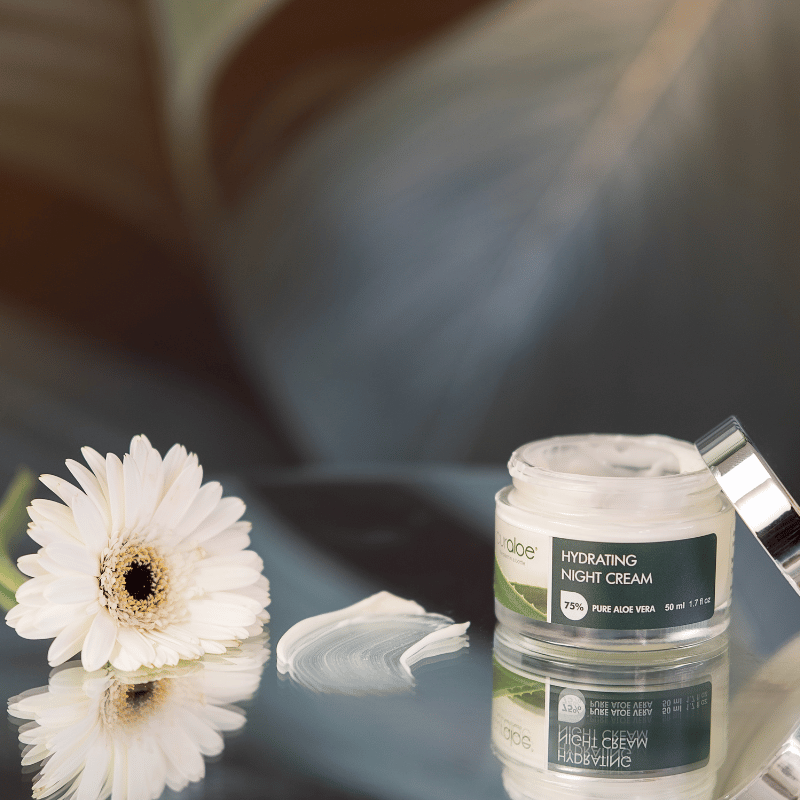 Curaloe Hydrating night cream jar with a white flower on a reflective surface