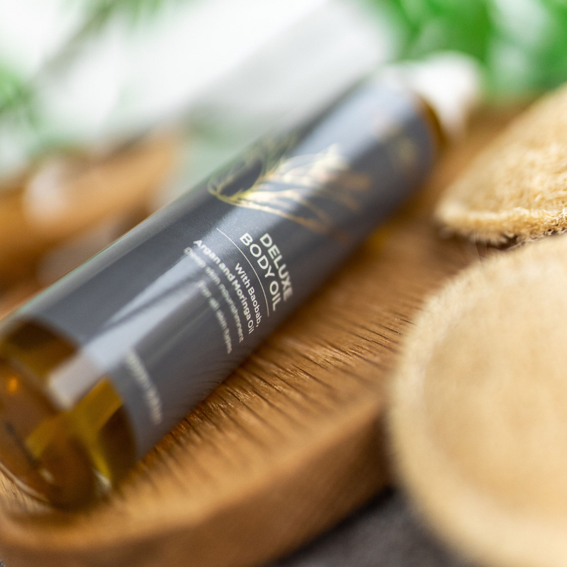 Curaloe Body oil bottle on a wooden surface with a blurred natural background