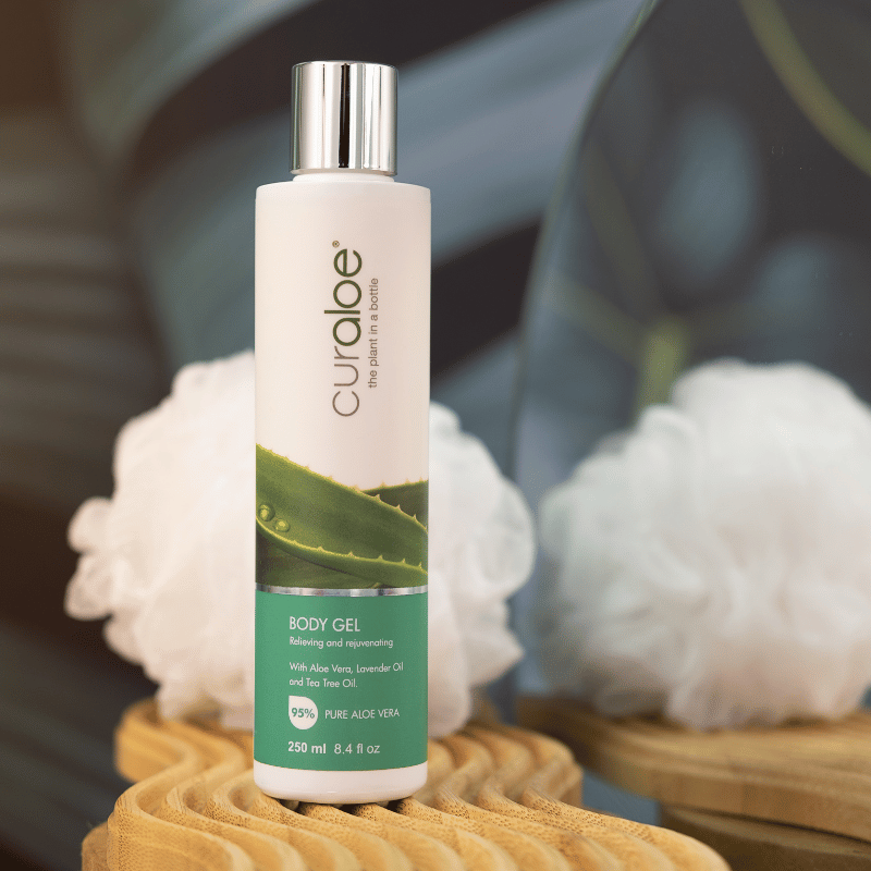 Curaloe body gel bottle with aloe vera illustration on a blurred background