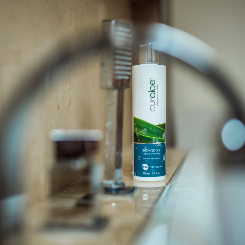 Curaloe shower gel bottle on a bathroom counter with blurred background
