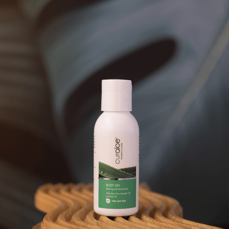 White bottle of Curaleaf body gel on a woven surface with a blurred leaf background